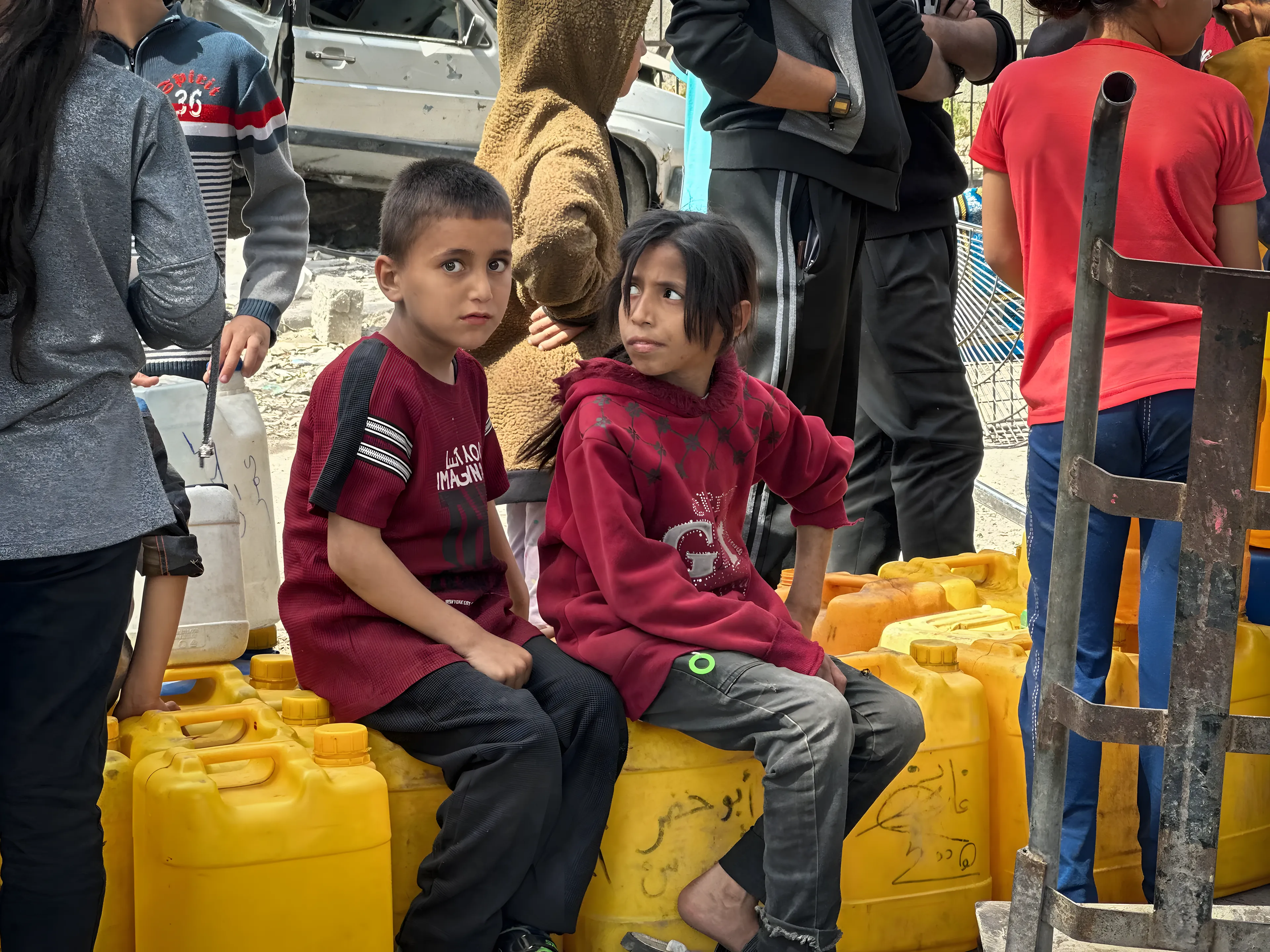 Enfants et familles avec des bidons d’eau.